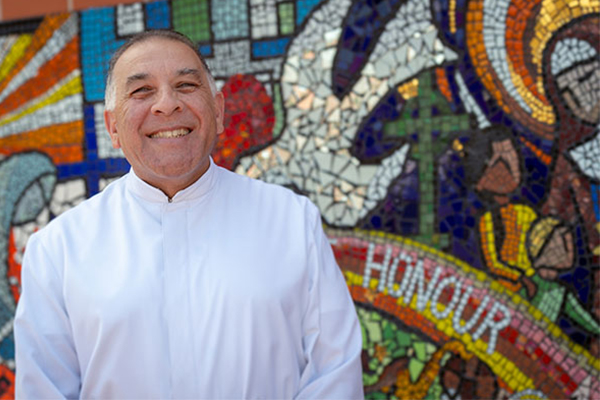 Br Nicholas Harsas standing in front of colourful mural smiling